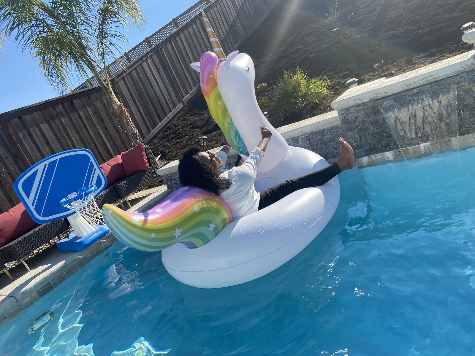 Michele Faith stretched out flat on a unicorn float in a pool